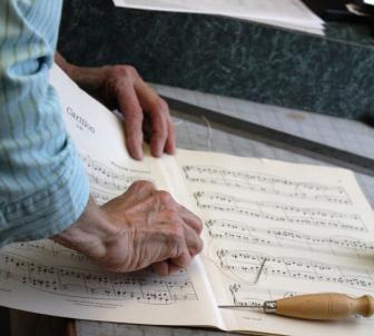 Music librarians mend aged sheet music. 